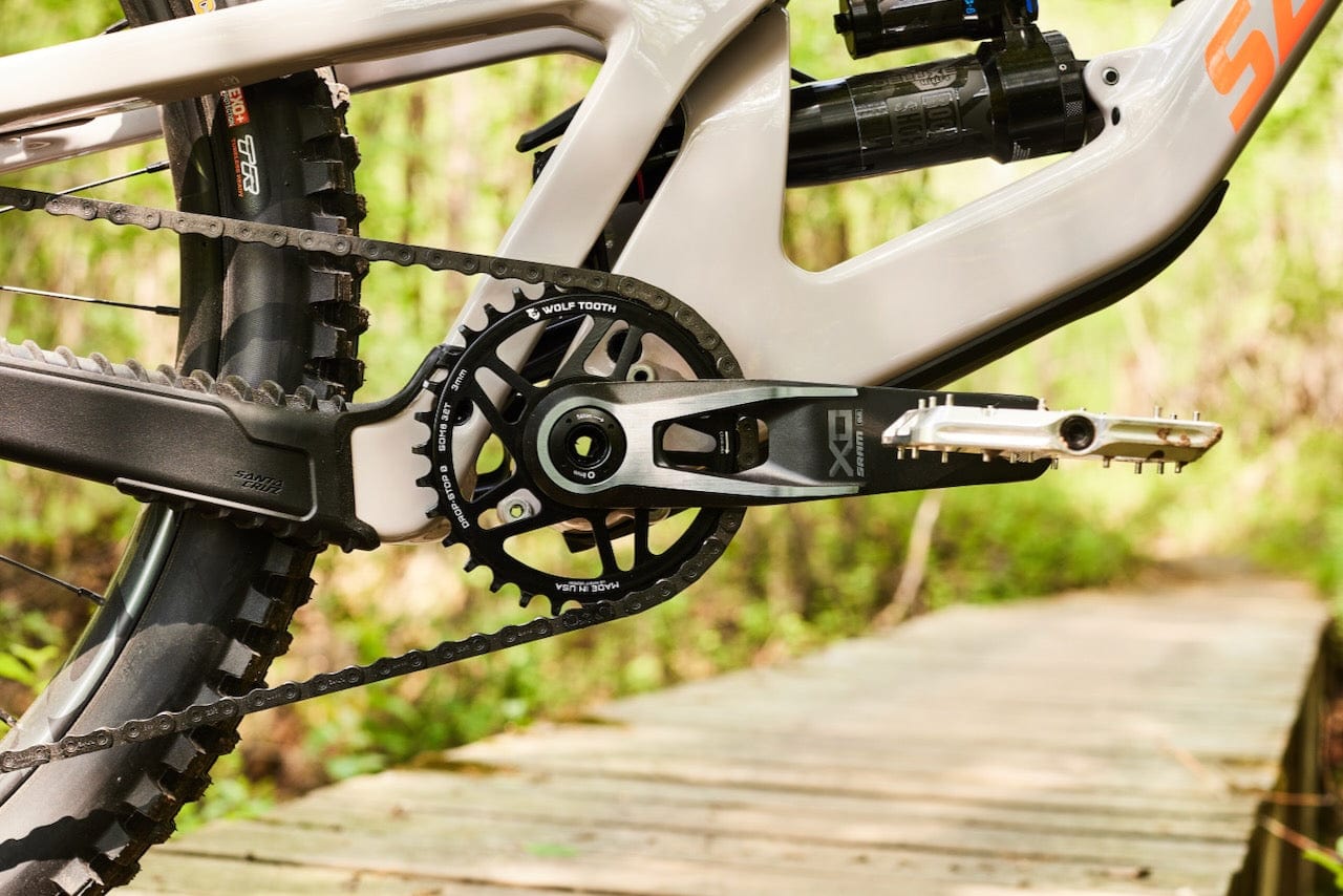 Closeup of a Wolf Tooth Drop-Stop B chainring from SRAM Transmission on a bike outdoors.