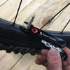 Wolf Tooth Pack Pliers, Master Link Combo Pliers, Black with Red Bolt, showed in use tightening valve stem lock nut on bicycle wheel