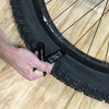 Wolf Tooth Pack Pliers, Master Link Combo Pliers, Black, showed in use removing tire on bicycle wheel