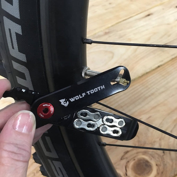Wolf Tooth Pack Pliers, Master Link Combo Pliers, Black with Red Bolt, showed in use removing the valve core on a bicycle wheel