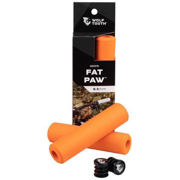 Wolf Tooth Fat Paw handlebar grips in orange both in packaging and sitting in front of packaging with bar end plugs